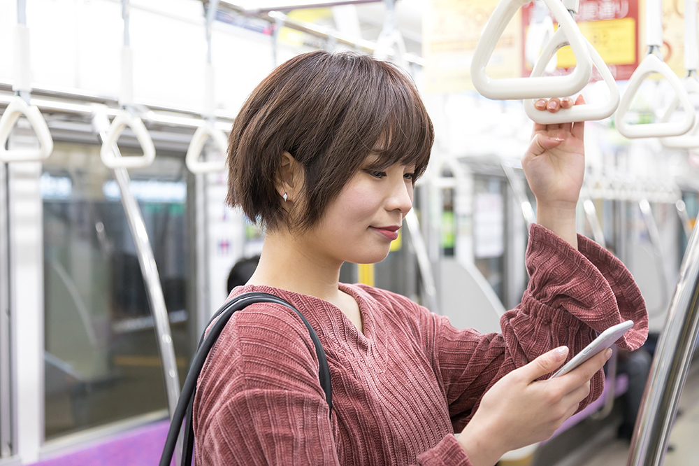 スマホを見ながら電車に乗る女性